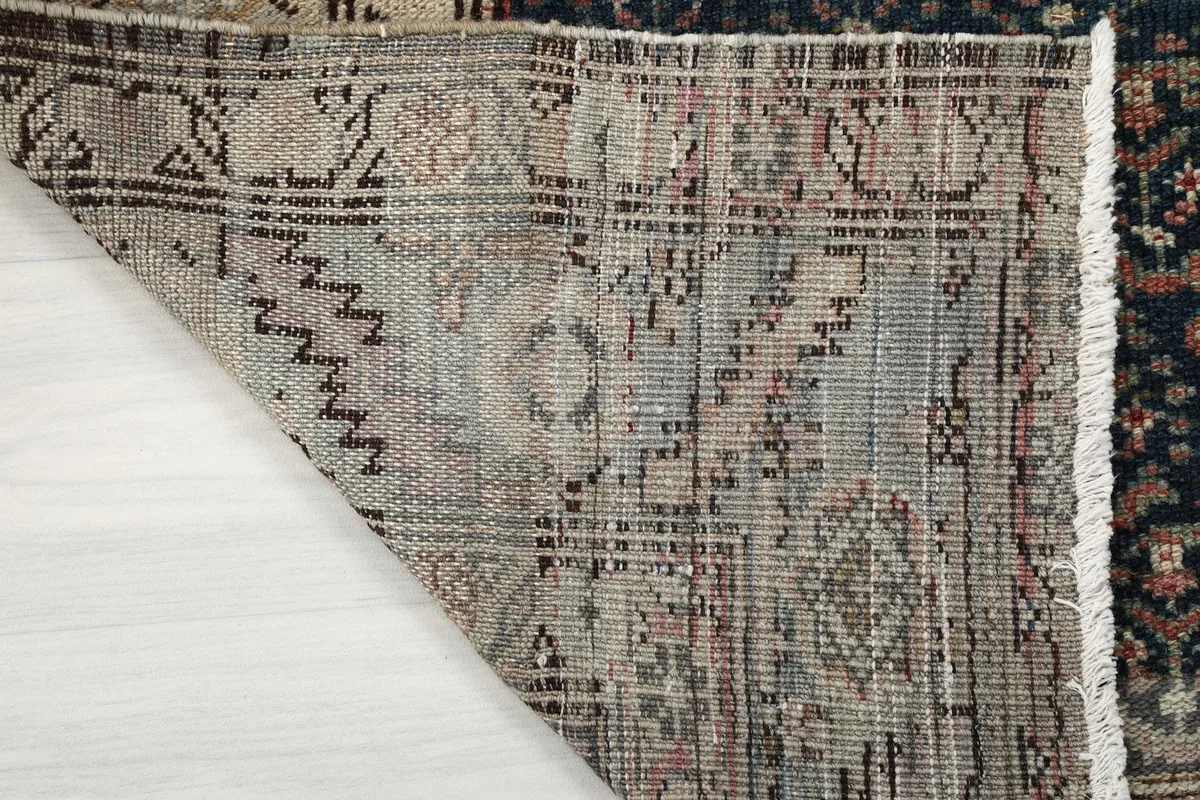 Corner of the rug lifted to display the backing and construction details