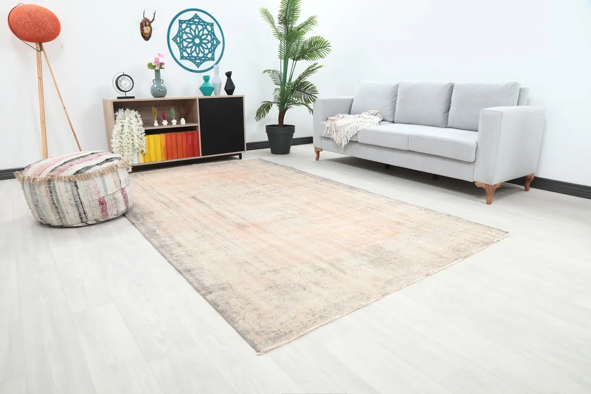 Angle view of the distressed pink and gray rug in a living room, showing its placement with furniture