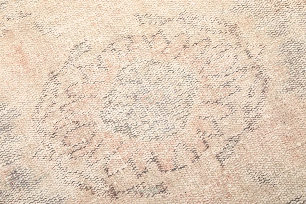 Close-up of the intricate, faded geometric pattern within the medallion design of the rug