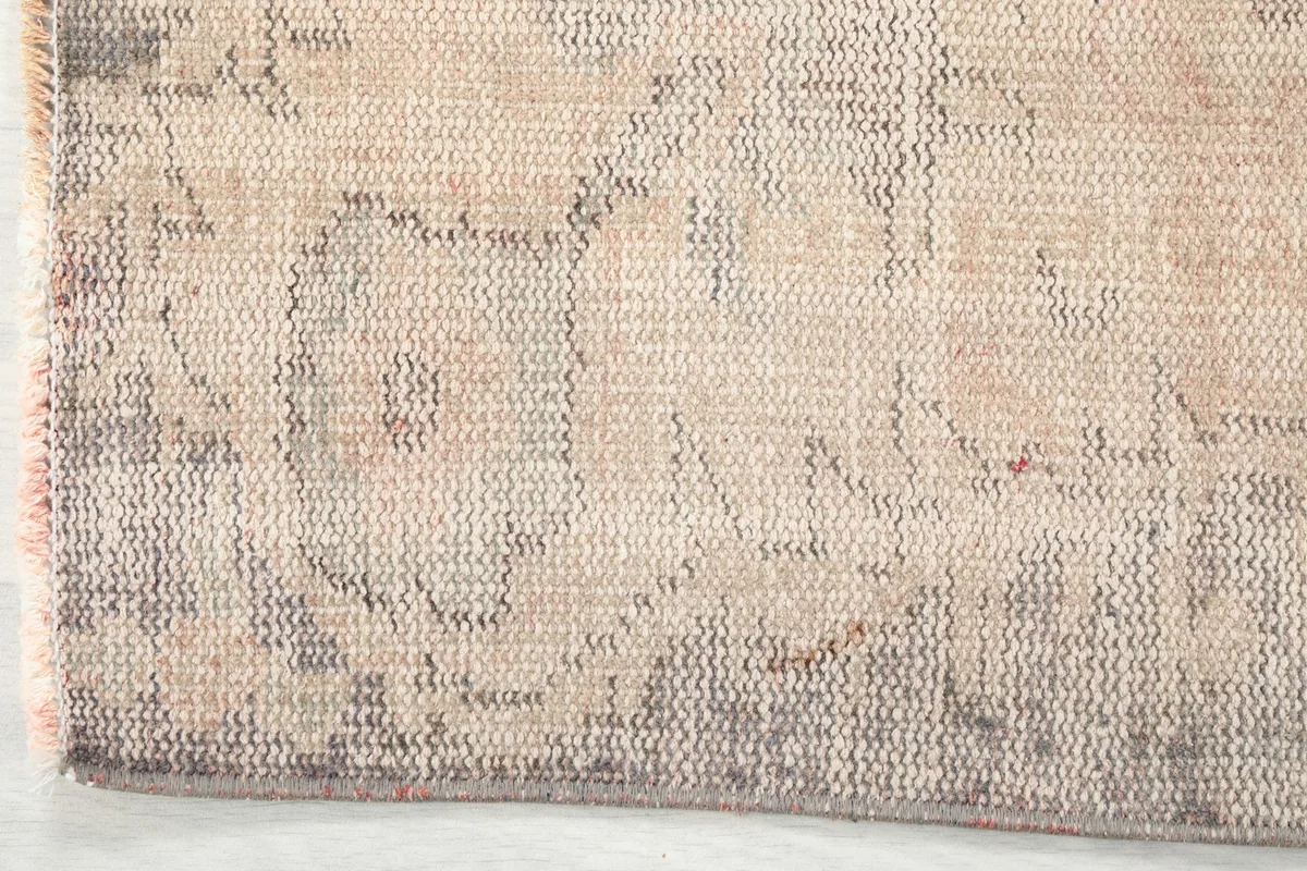 Detailed view of the rug's border showing the texture and muted gray and beige tones