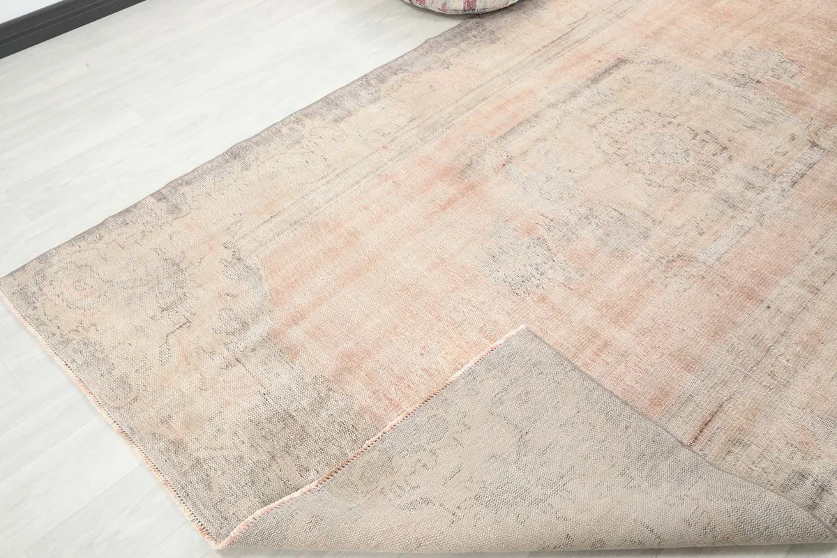 Corner of the vintage rug folded back, revealing the wool pile and cotton foundation