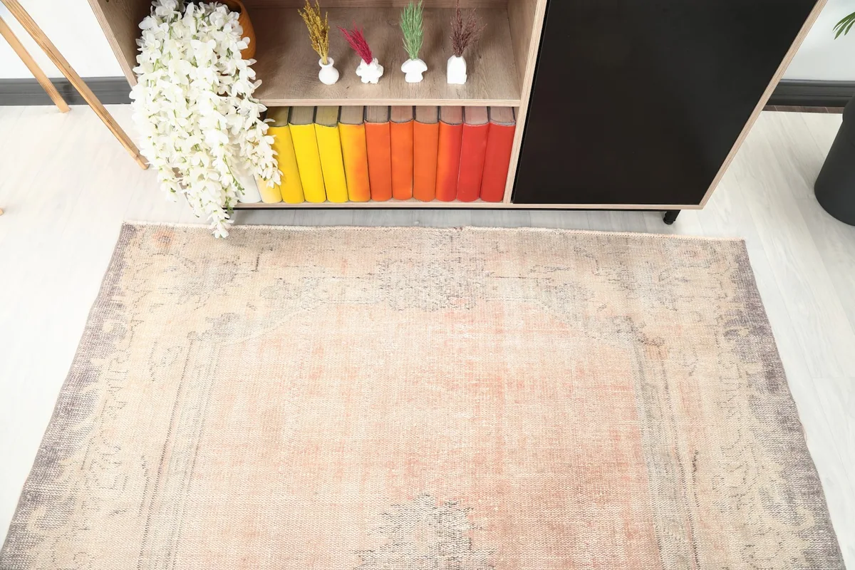 Overhead view showing the distressed pink field and gray border of the hand-knotted rug