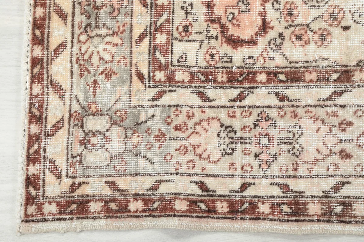 Close-up of the rug's border, showcasing the geometric and floral elements with patina