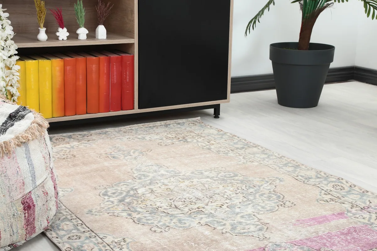 Close-up angled view of the rug's pattern and colors next to a striped pouf