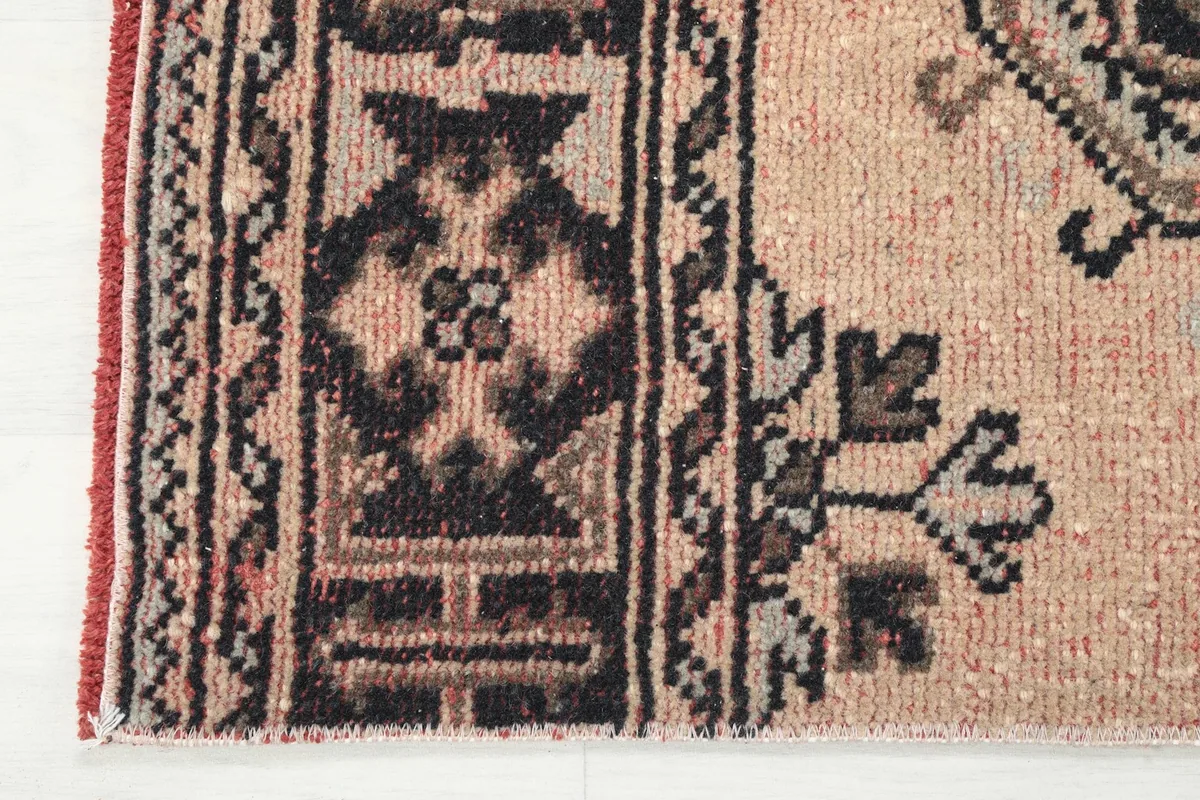 Close-up of the rug's end border, showing the intricate design and red edge stitching.