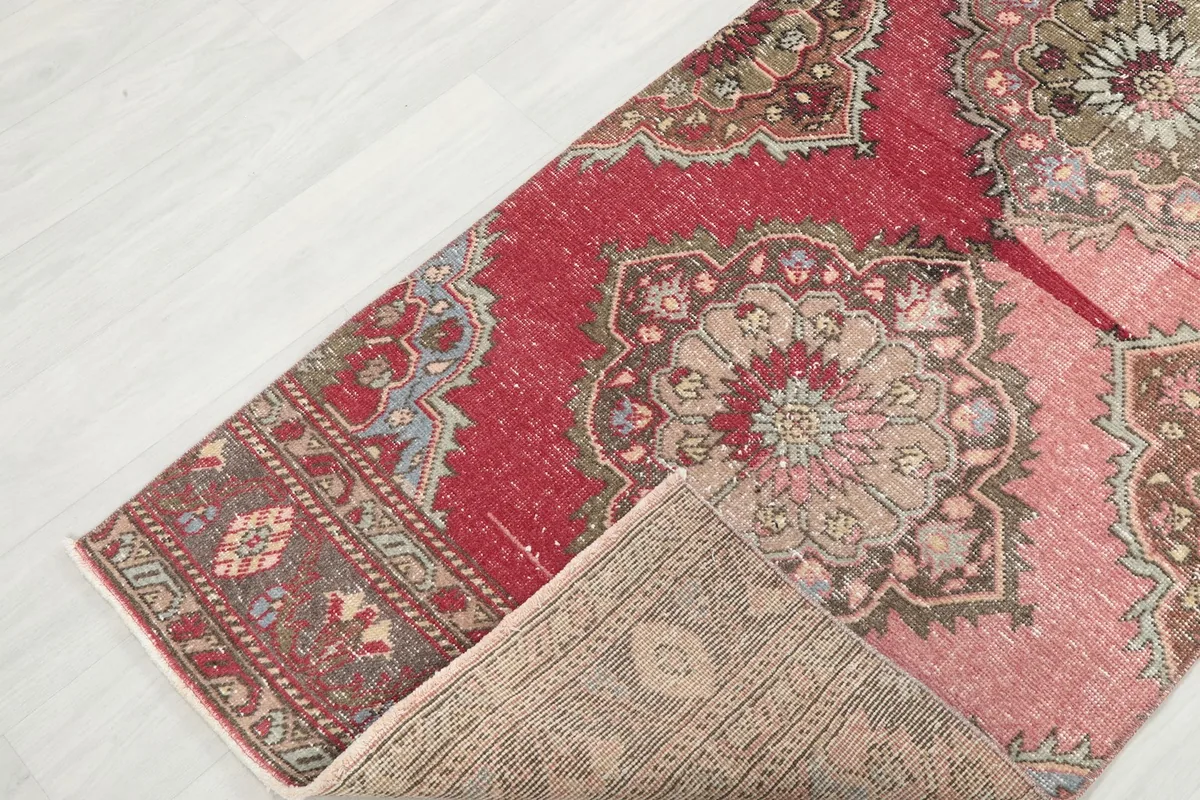 Corner of the runner rug folded back, revealing the reverse side and knotting