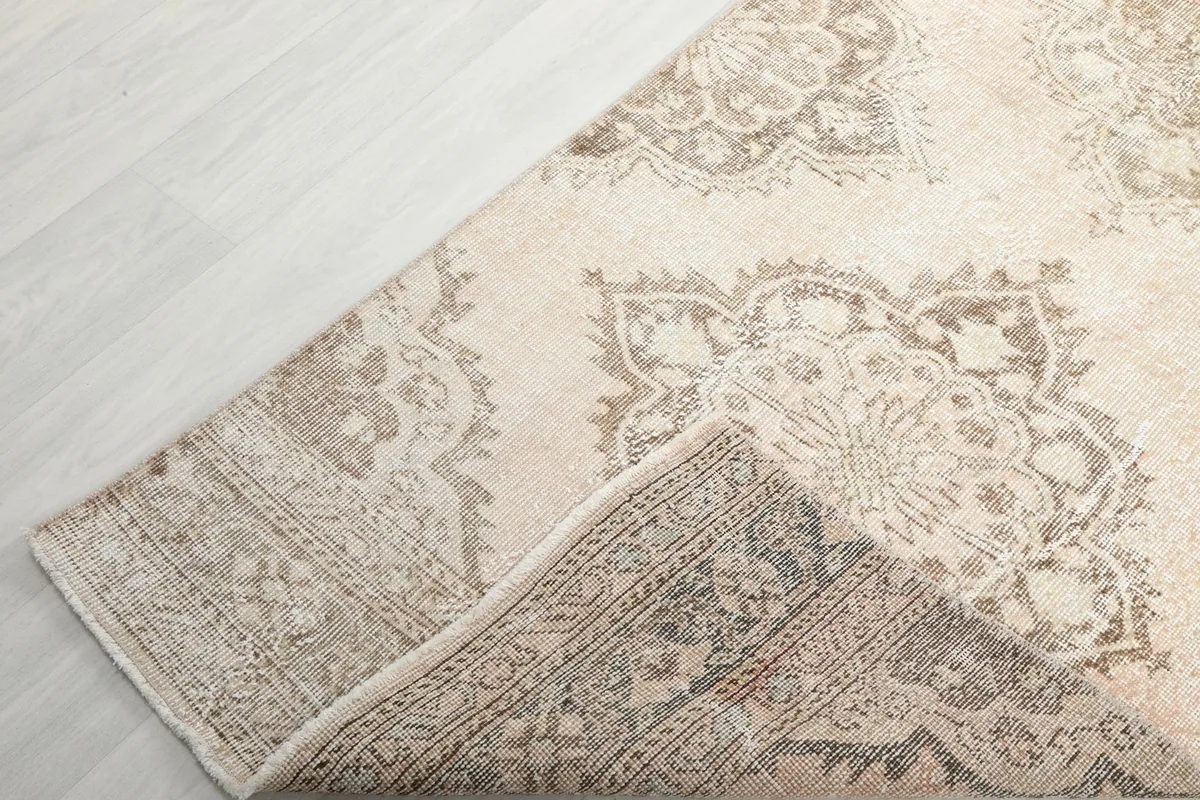 Corner of the runner folded back to reveal the back of the rug and the foundation.