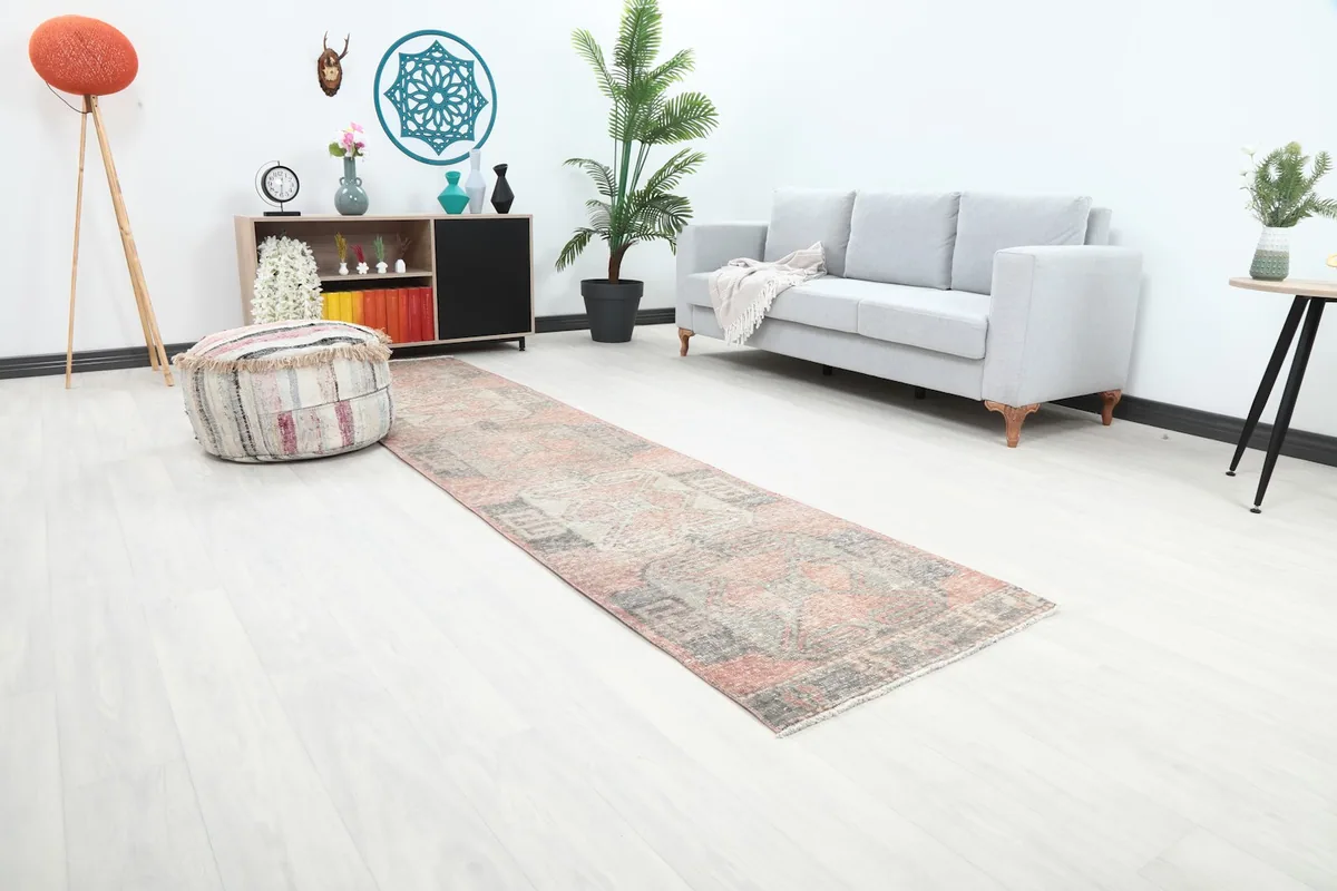 Angle view of the rose and gray runner rug extending from a seating area into a hallway.