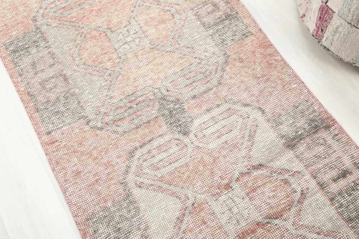 Detailed view of the rug's surface, highlighting the rose, gray, and beige geometric motifs.