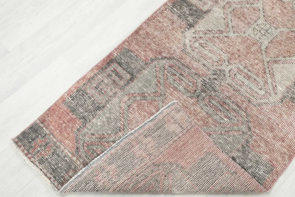Corner of the rug folded back, revealing the reverse side and the hand-knotted construction.