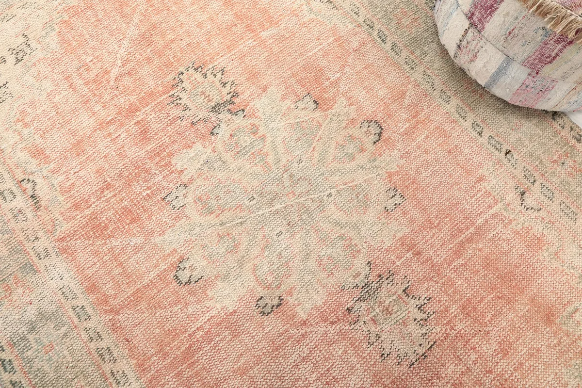 Detailed view of the central medallion and the faded rose field with signs of vintage patina.