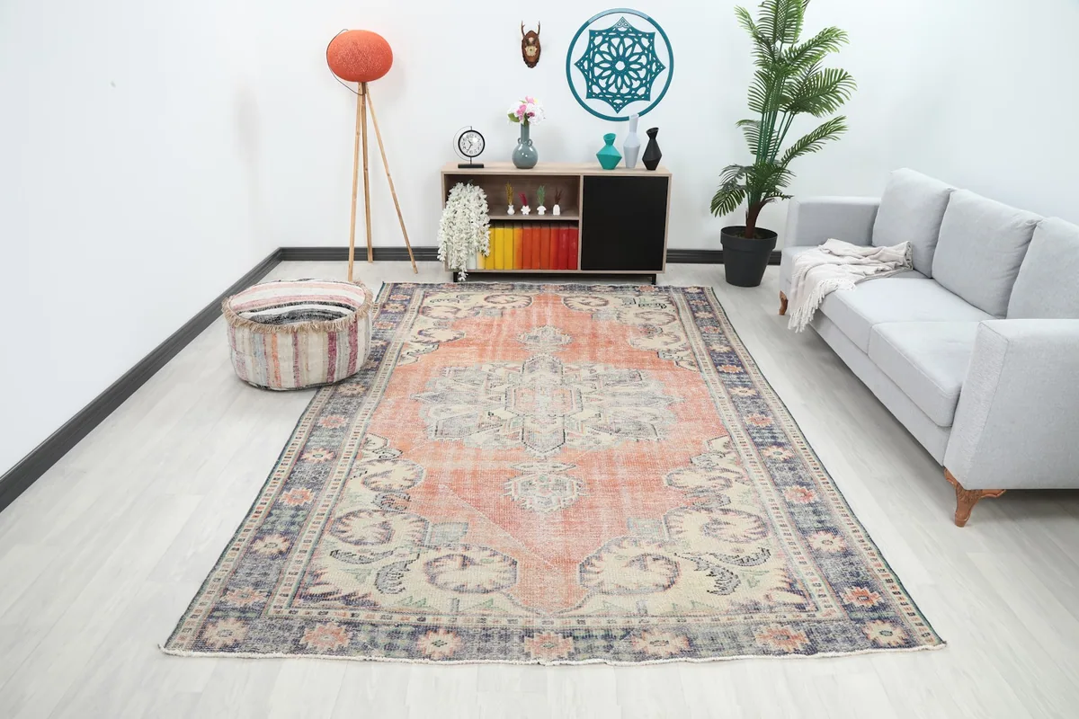 Vintage rust and navy medallion rug placed in a modern living room setting with a gray sofa