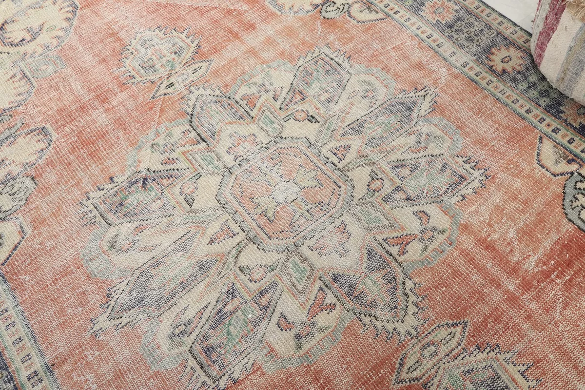 Close-up detail of the central medallion, showing faded blue, ivory, and rust tones in the pattern
