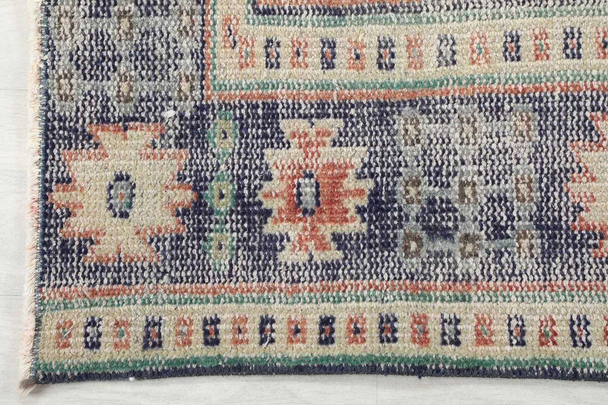Detail of the navy border with geometric patterns and fringe along one edge of the rug