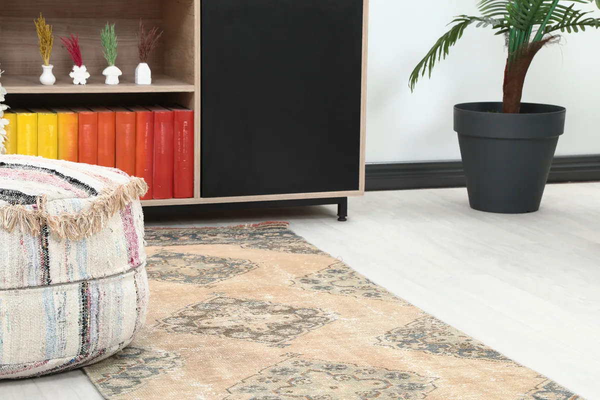 View of the Warm Beige Geometric Anatolian Runner's faded texture next to furniture