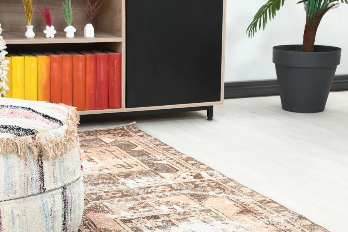 Close-up of the runner rug's end in a room, showing its texture next to a pouf and cabinet.