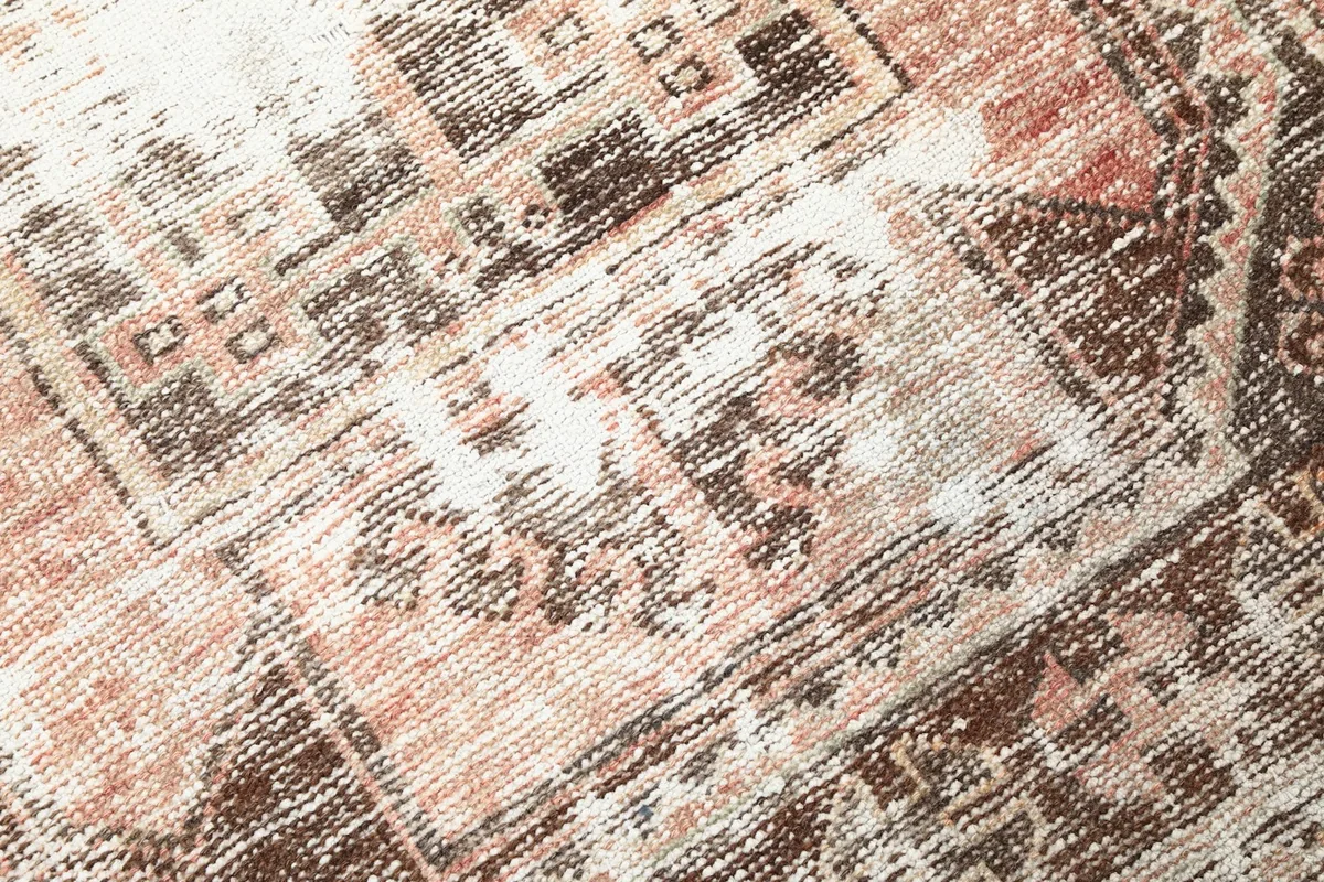 Detailed view of the wool pile and distressed areas, showing the blend of rose, brown, and beige.