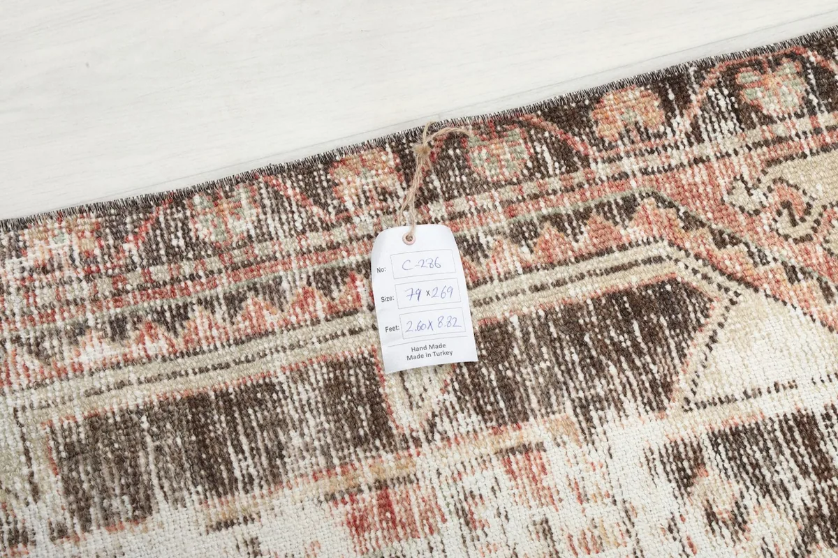 Detail of the rug with a tag, showing the texture and colors of the hand-knotted vintage piece.