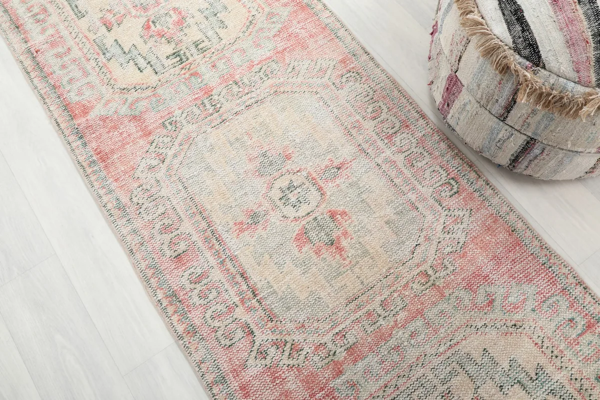 Angled close-up of the runner's faded rose field and cream medallion, revealing the distressed texture.