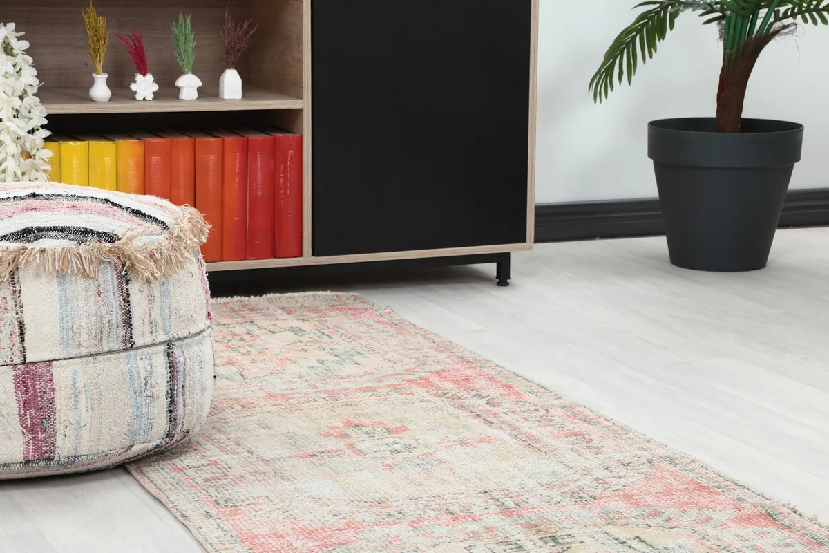 Close-up view of the runner rug's texture and patterns near a decorative ottoman and cabinet.