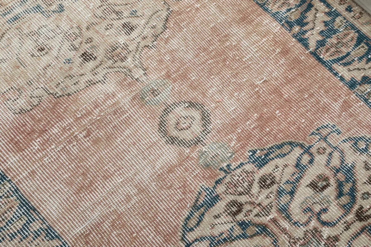 Detailed close-up of the rose field and navy medallion, showing the low pile and vintage wear