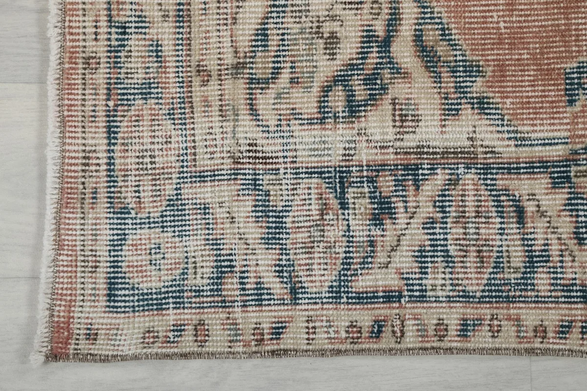 Close-up of the rug's border and fringe, highlighting the navy and beige patterns