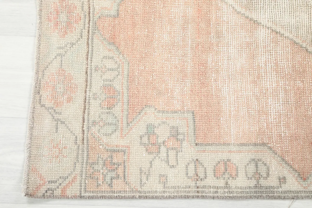 Corner detail of the rug showing the orange field and beige border patterns