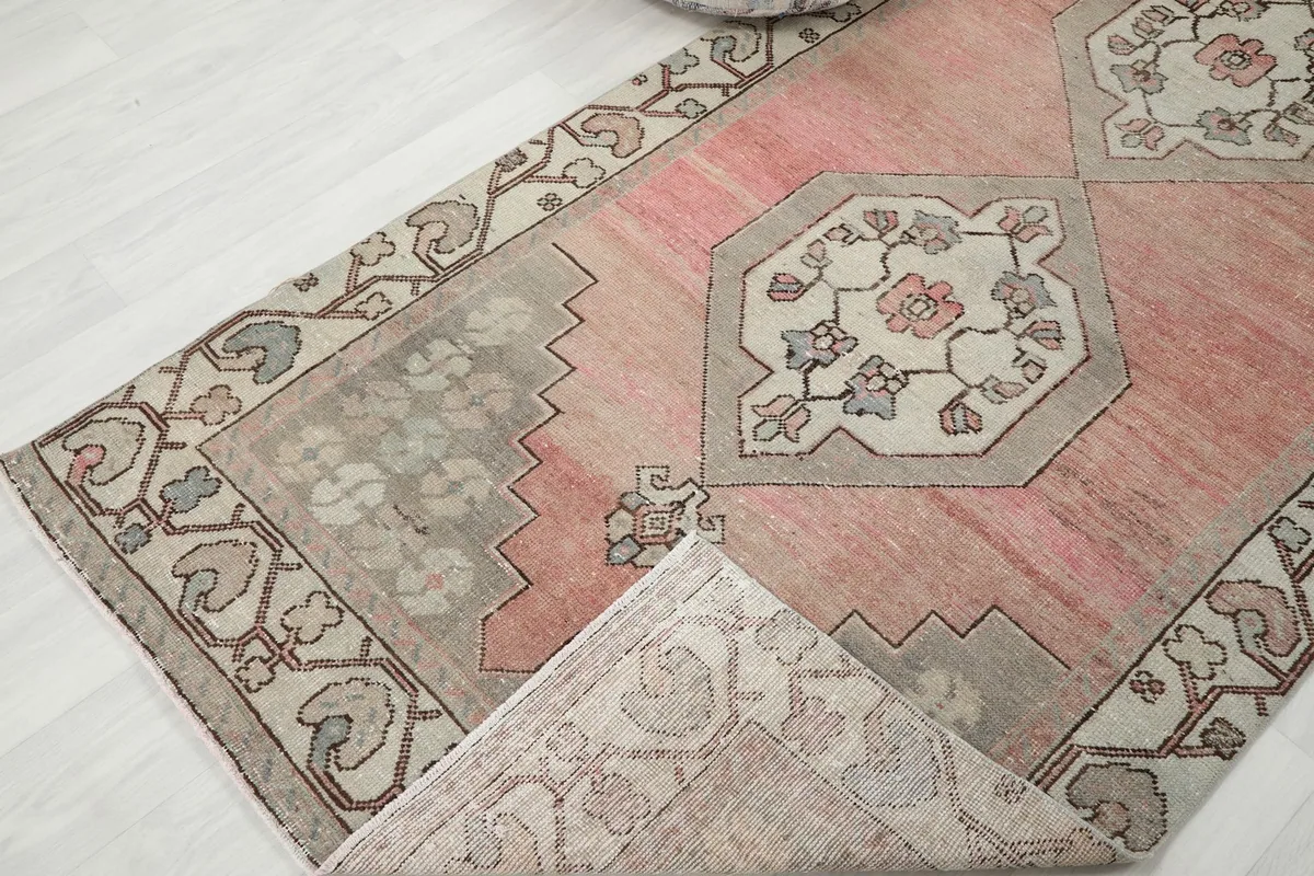 Corner of the rug folded back, revealing the reverse side and the hand-knotted construction.