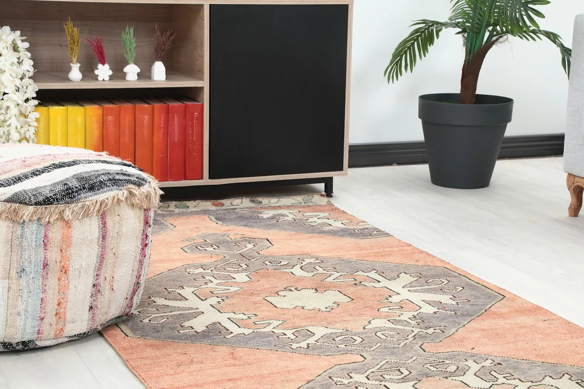 Close-up view of the runner rug in a room, showing its motifs near a wooden cabinet and pouf