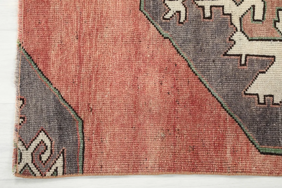 Close-up of the rug's edge, revealing the hand-knotted texture and the subtle color shifts in the rust field