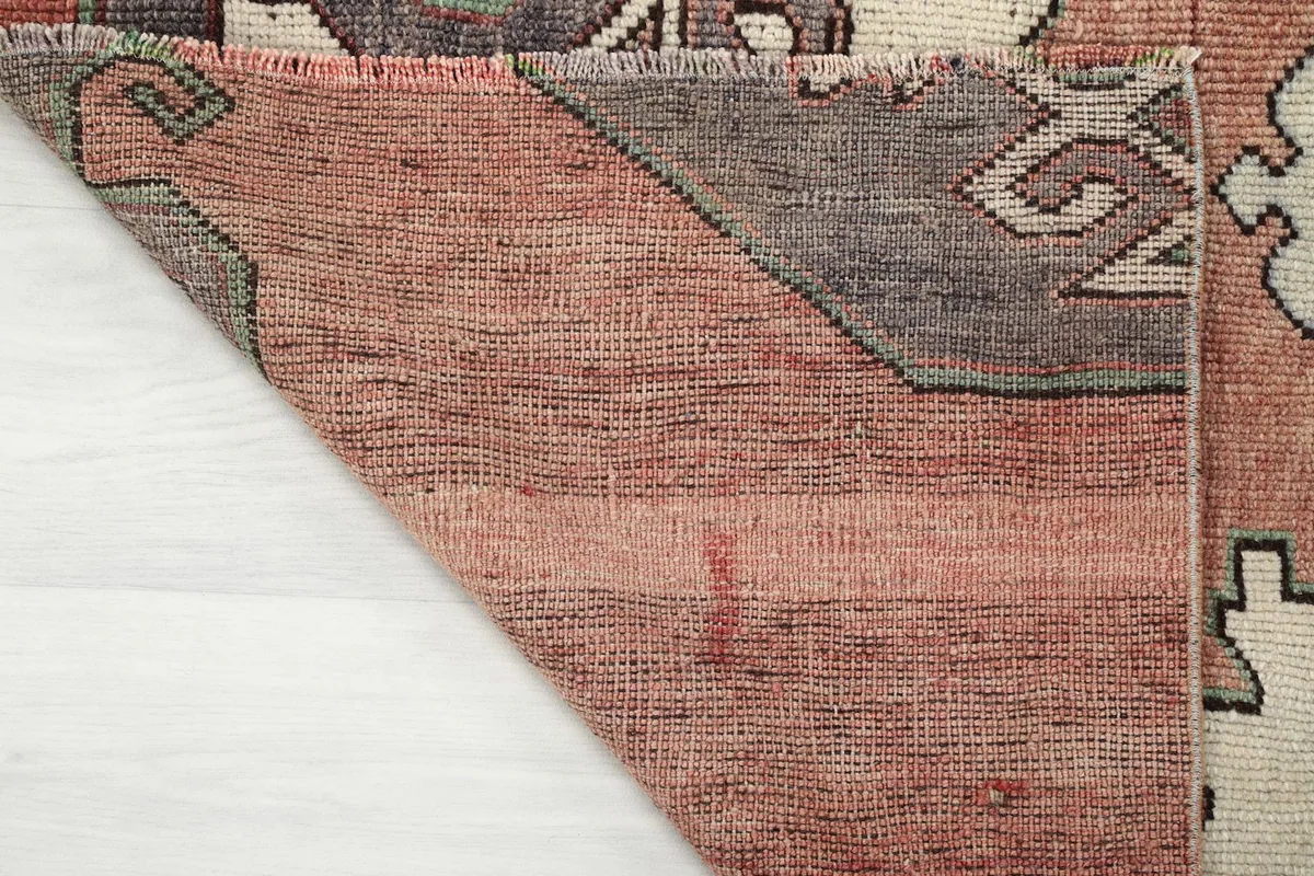 Underside corner of the rug, showing the cotton foundation and the reverse of the hand-knotted pile