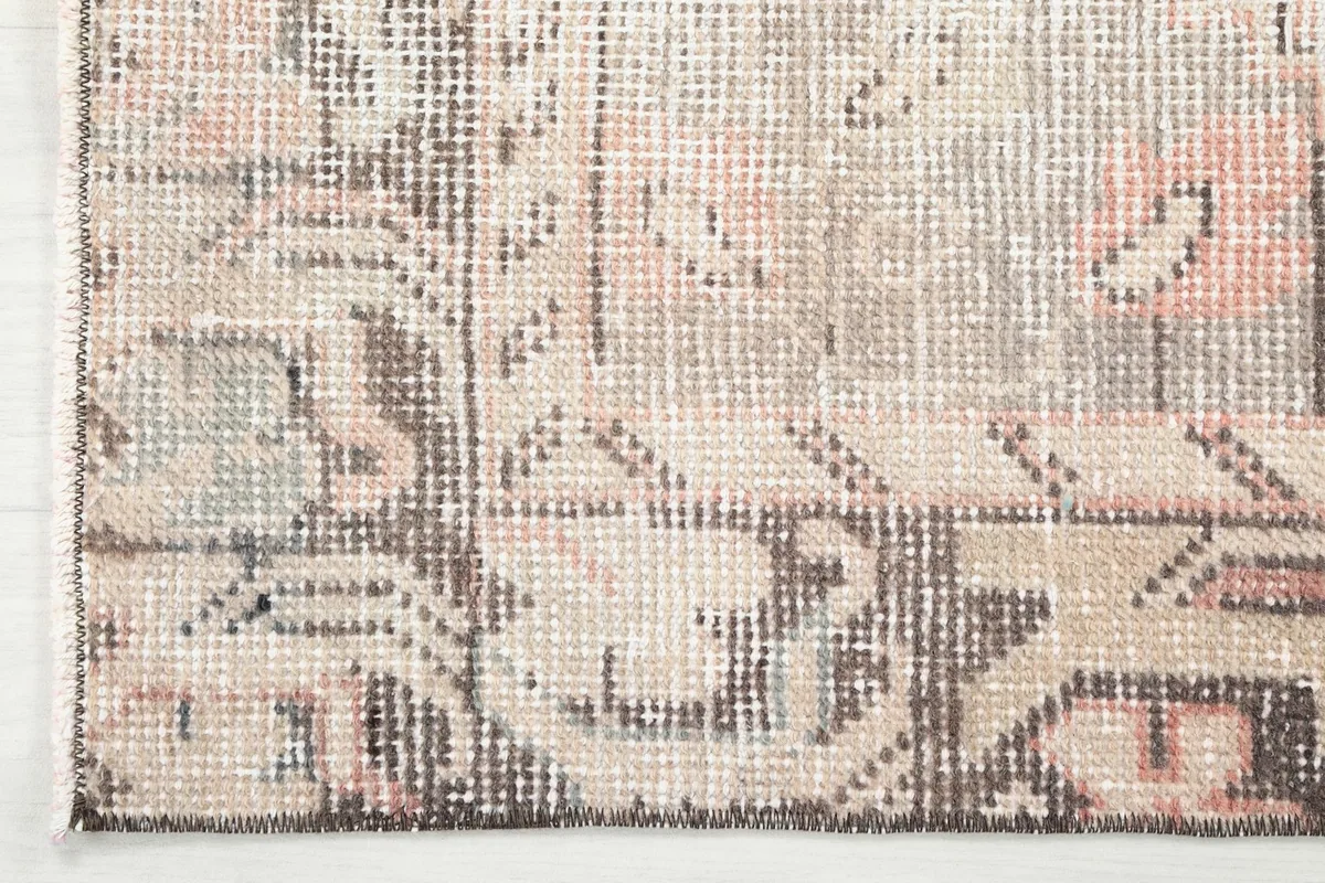 Detailed view of the rug's border design with brown and gray tones