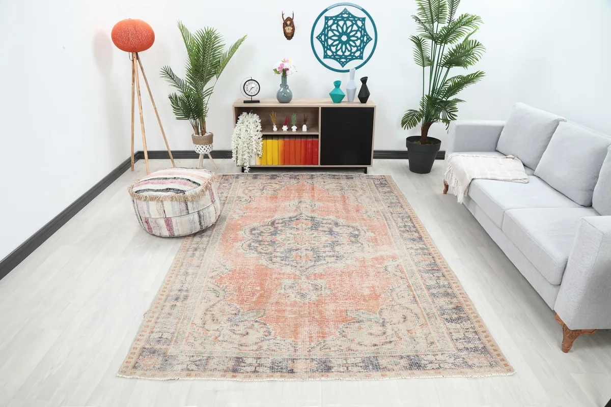 Vintage orange and blue rug displayed in a living room setting with a sofa and ottoman