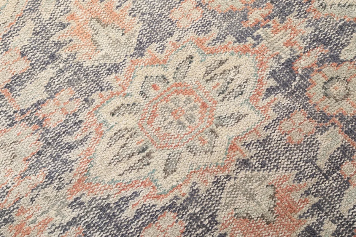 Close view of the low wool pile texture and faded colors of the rug surface