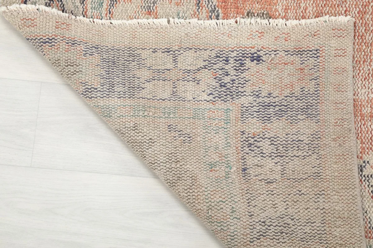 Underside of the rug with a corner folded back, revealing the cotton foundation