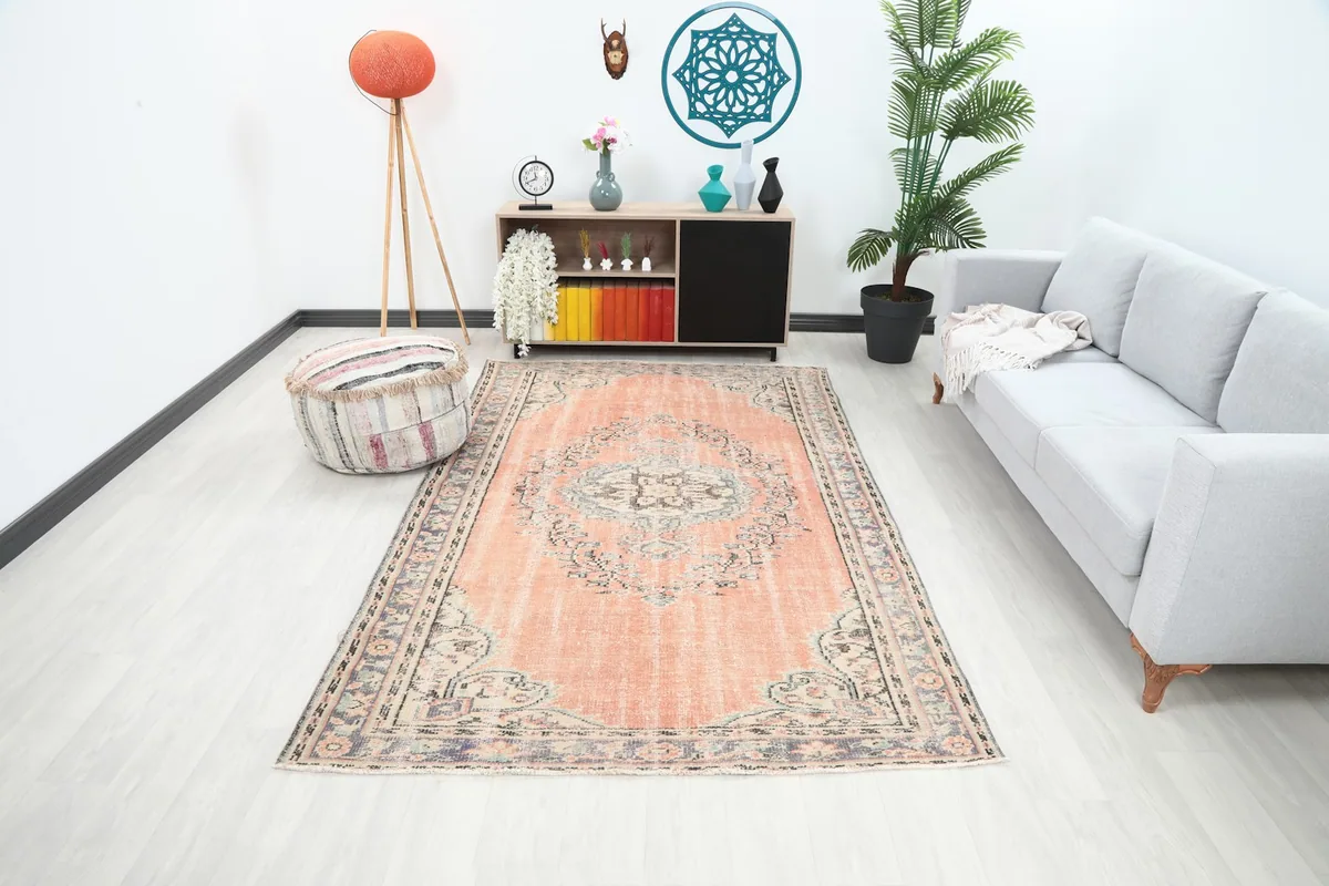 Orange Anatolian area rug in a modern living room setting with a gray sofa and wooden cabinet