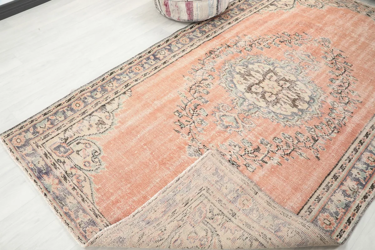 Angled view of the orange rug with a corner folded back, revealing the reverse side of the weave