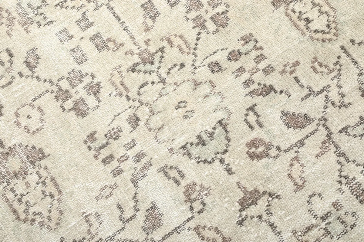 Detailed close-up of the hand-knotted wool pile, showing the beige background and gray patterns.