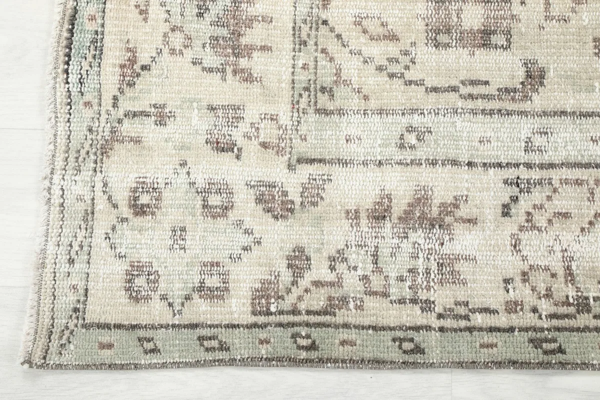 Close-up of the rug's edge and border design, with subtle green accents visible.