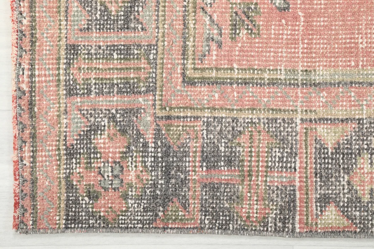 Corner detail of the Faded Rose Geometric Anatolian Runner, showing the gray border with tribal motifs.