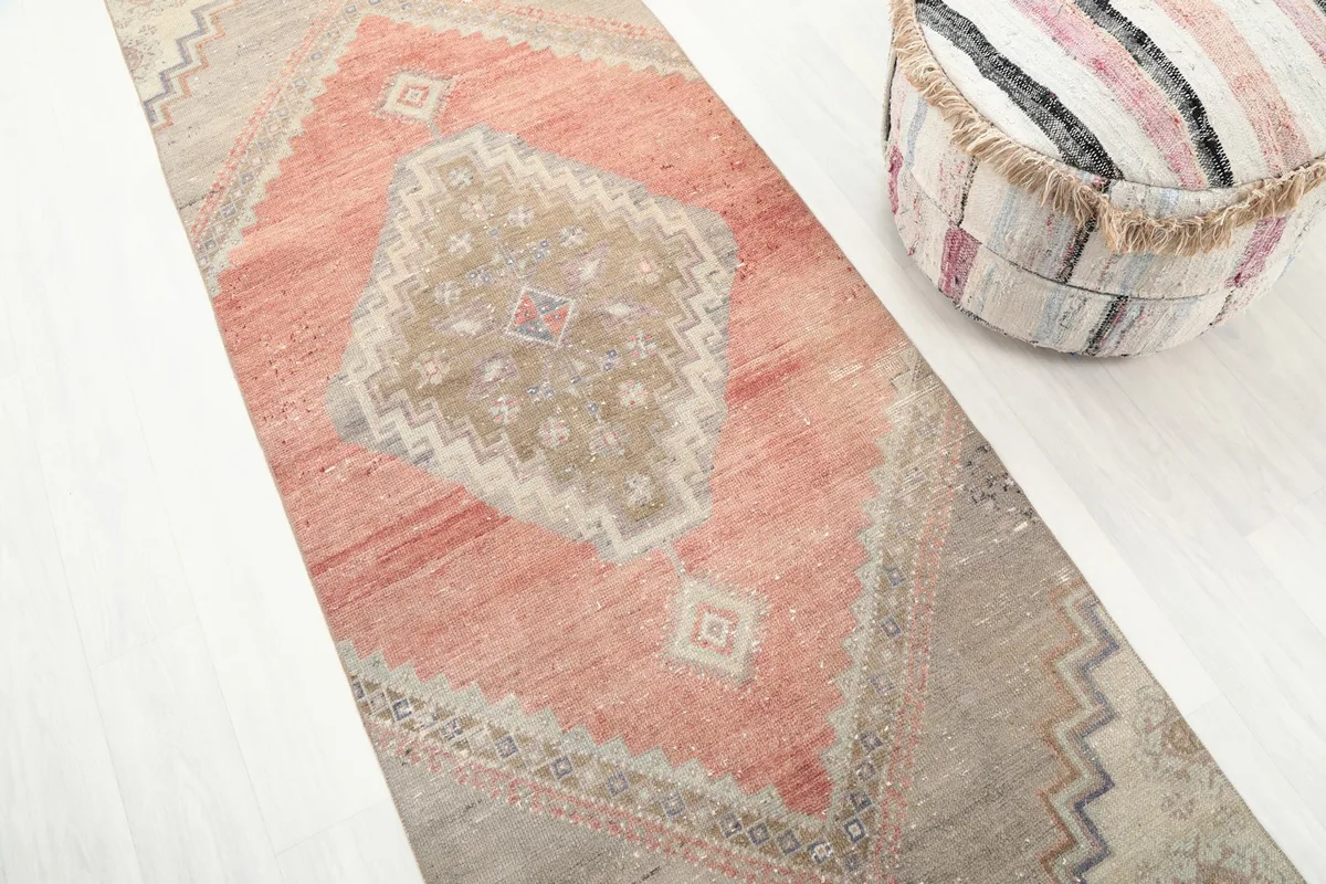 Diagonal view of the runner rug, emphasizing the faded rust and beige colors and geometric patterns.