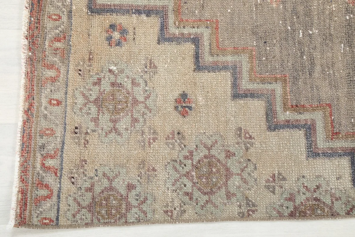 Close-up of the rug's end, revealing the border design, fringe, and subtle color shifts in the wool pile.