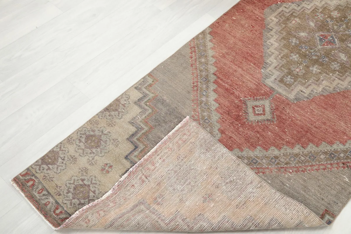 Corner of the runner rug folded back, showing the wool pile on the front and the cotton foundation on the back.