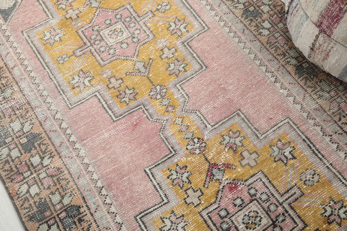 Detailed view of the pink and gold geometric motifs with visible wear and patina