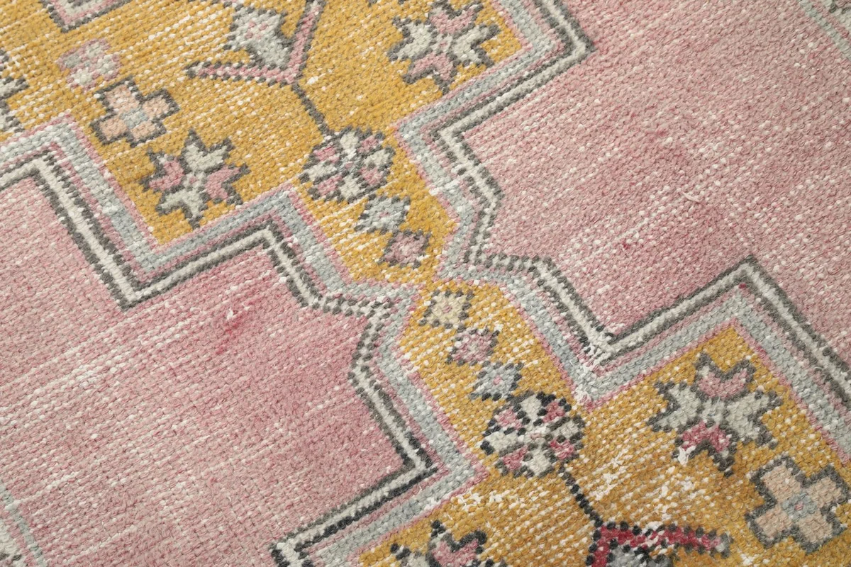 Close-up of the low wool pile and distressed texture on the pink and gold runner