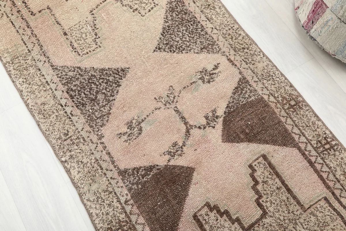 Angled close-up showing the texture and faded brown tribal patterns on the beige runner.
