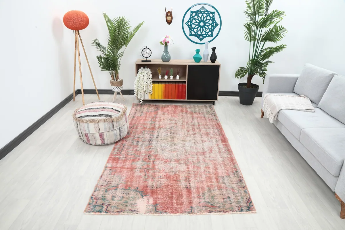 Vintage rose area rug displayed in a living room setting with a sofa and ottoman.