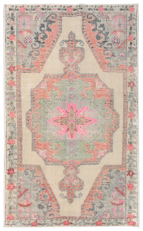 Full top view of the beige, pink, green, and orange medallion vintage Anatolian rug on a white background.