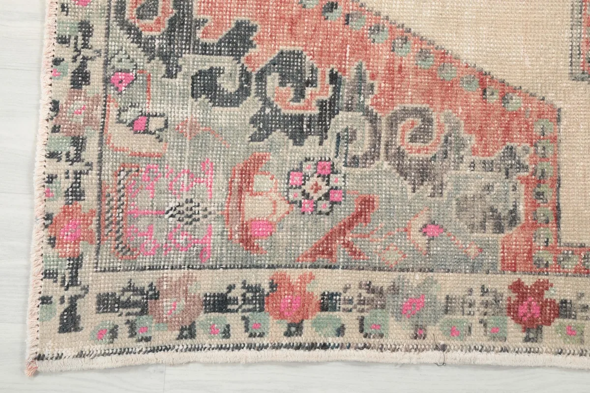 Close-up of the rug's border and corner, showing the intricate floral and geometric patterns in gray and black.