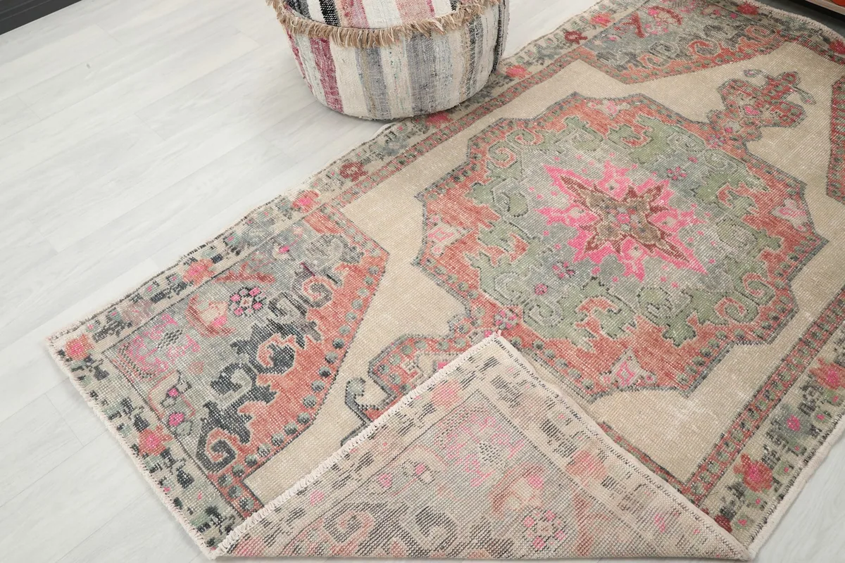 View of the rug with a corner folded back, revealing the reverse side and the hand-knotted construction.